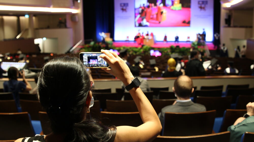 A graduate’s family member photographing the Commencement ceremony