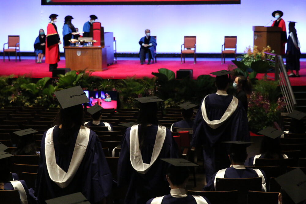 Graduates filing back to their seats after receiving their scrolls upstage