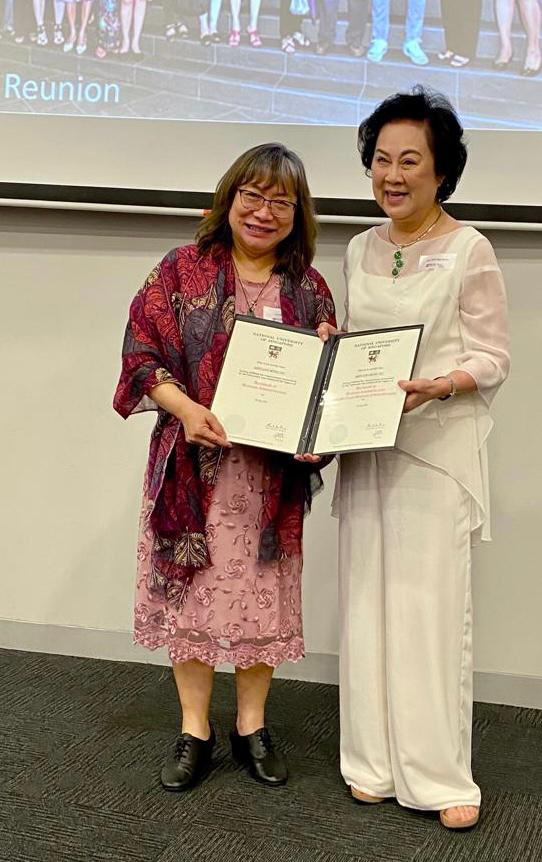 Prof Gan See Khem (right) presenting the commemorative degree scroll to a Class of 1981 alumna.